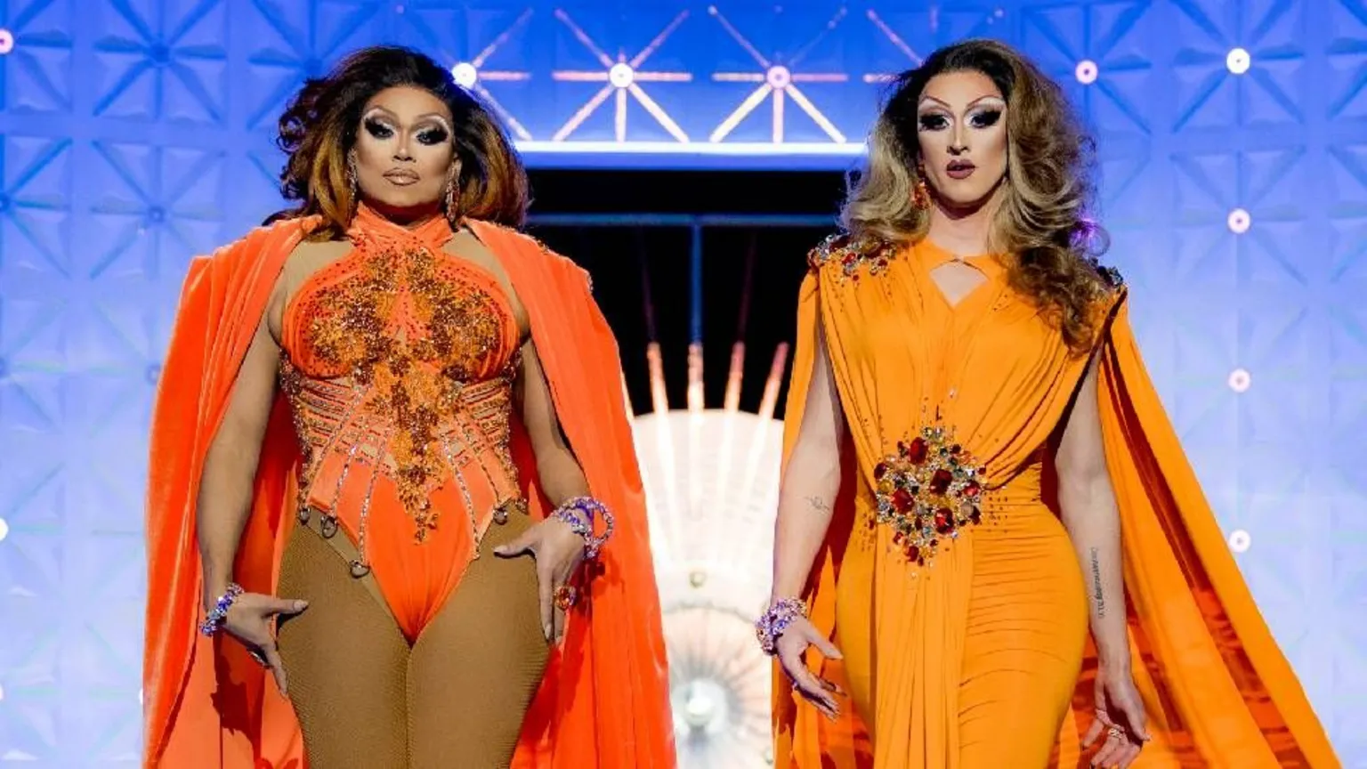 BBC/World of Wonder/Guy Levy Daniel Jervis pictured alongside drag queen Mariah Balenciaga. The pair are in full drag and wearing orange gowns.