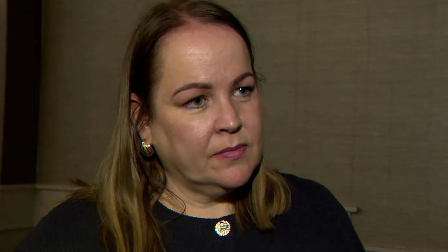 Joleen Cunningham has medium-length blond/brown hair and is wearing a dark buttoned up top