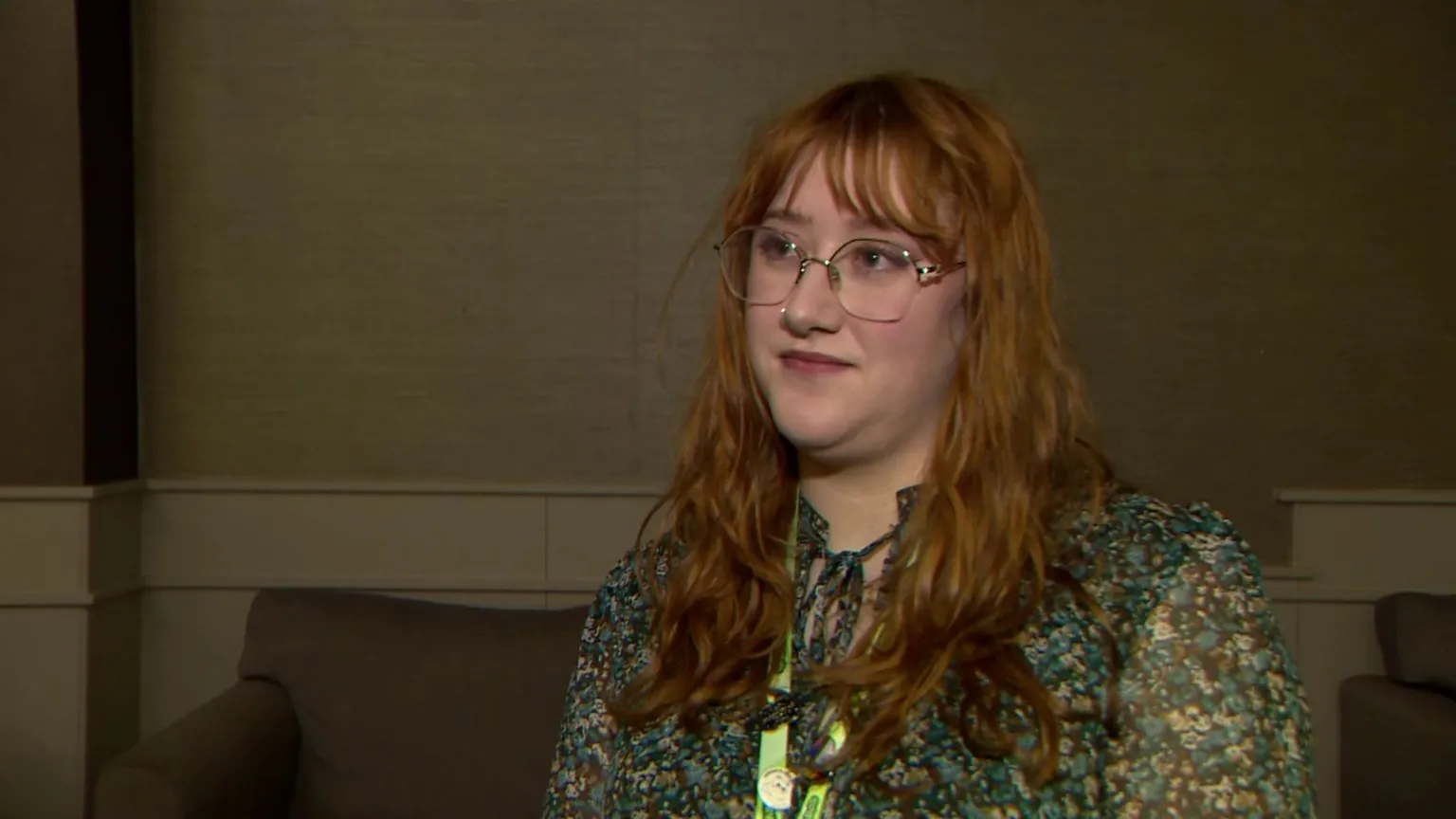 Megan Stith has long red hair and light-framed glasses and is wearing a floral blouse