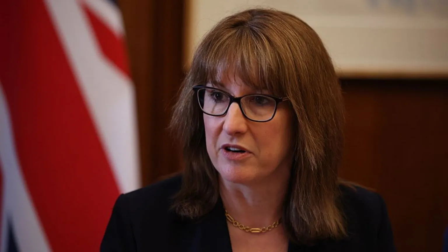  UK Chancellor Rachel Reeves wearing glasses and a black suit jacket.