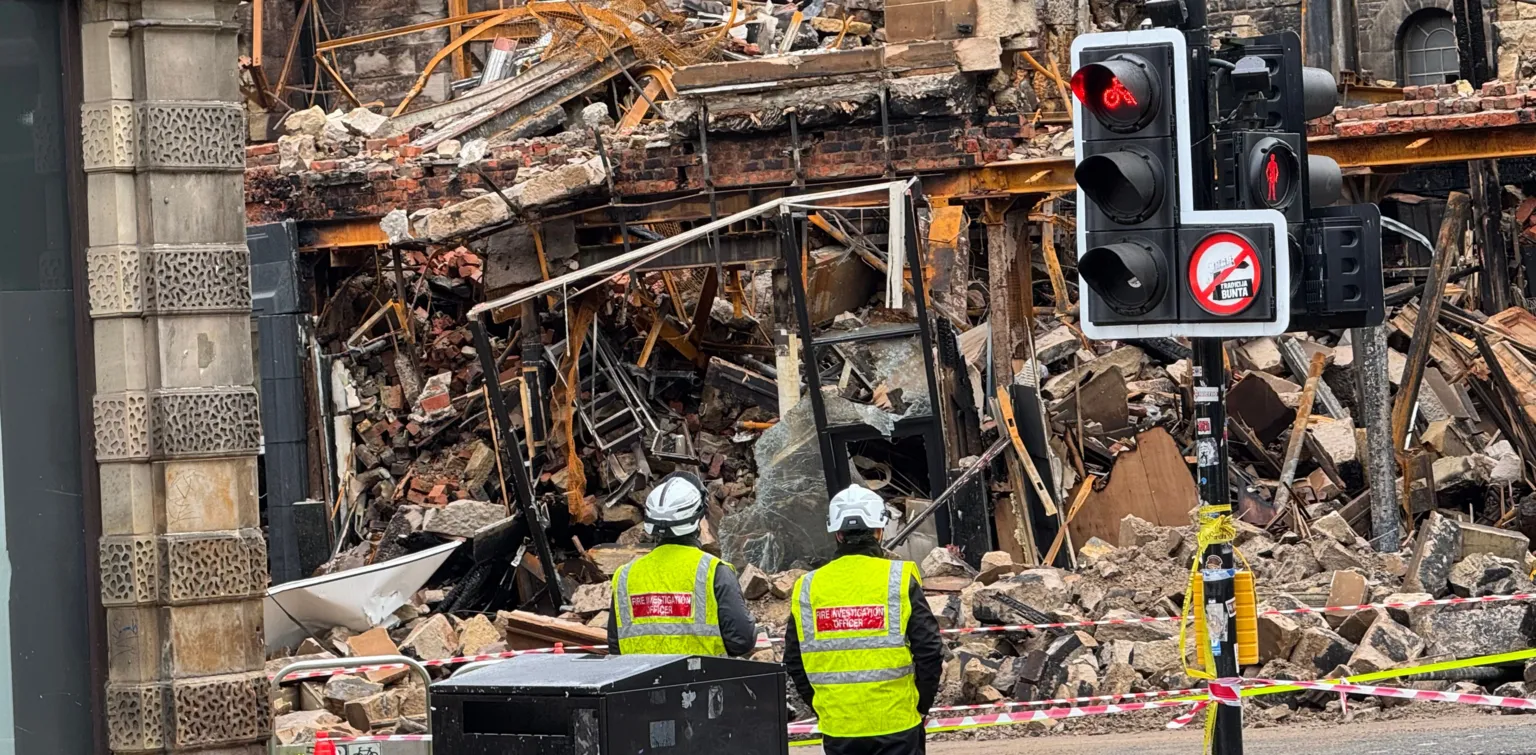 A field of debris with workmen standing in front of it in Glasgow