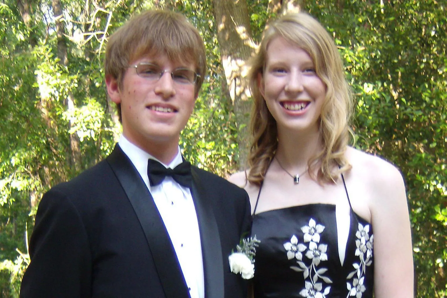 Kate Grosmaire Photo of Conor McBride, in a black tie and jacket and white shirt, and Ann Grosmaire, in a black dress with white flowers, smiling at the camera