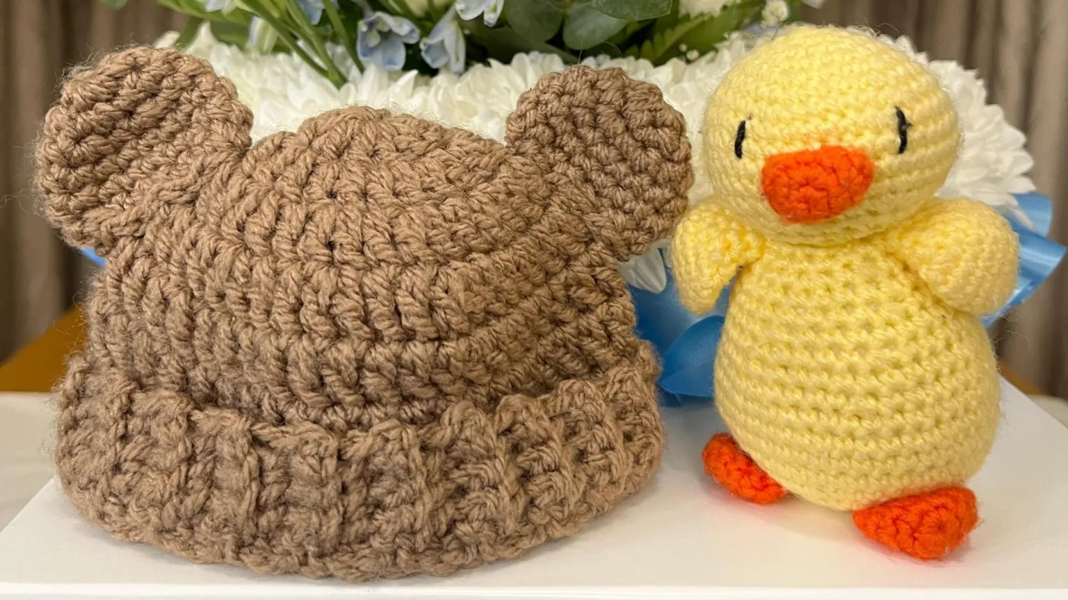 Maddie Biggs A knitted, brown woolen hat with teddy bear ears is next to a yellow knitted toy duck