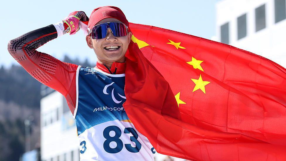 Chinese Para-biathlete Jiayun Cai celebrates with the Chinese flag