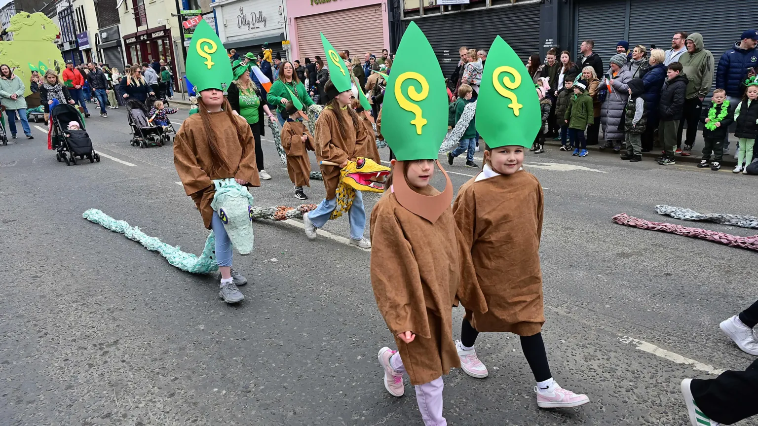 Pacemaker A group of children participating in the St Patrick's Day parade in Downpatrick. They are wearing brown robes and large green St Patrick hats. Two of them are carrying large fake snakes.