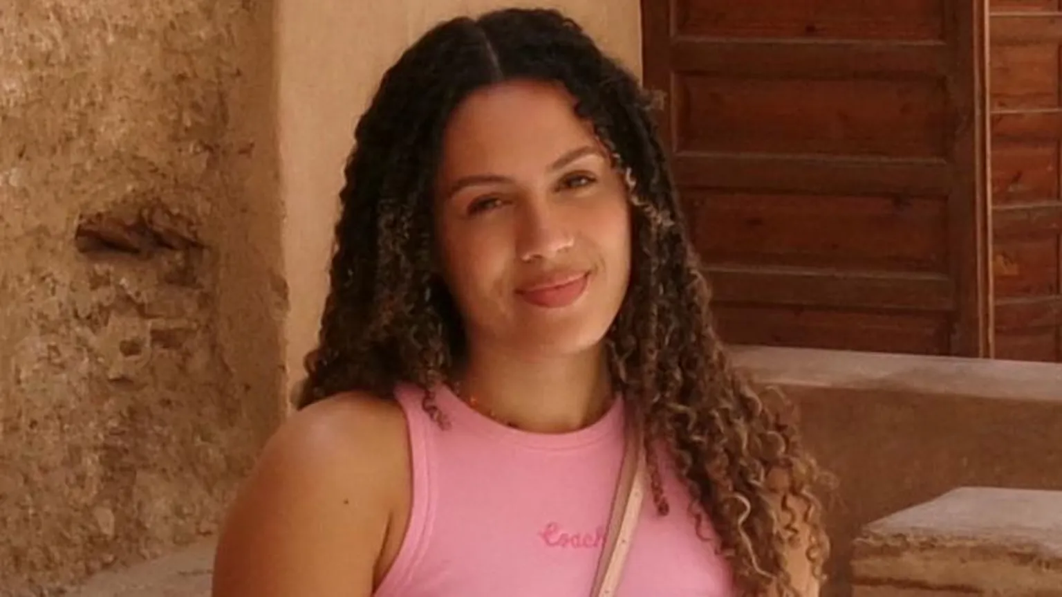 Image supplied Rochelle, a woman with long curly brown hair in a middle parting, wearing a pink vest top