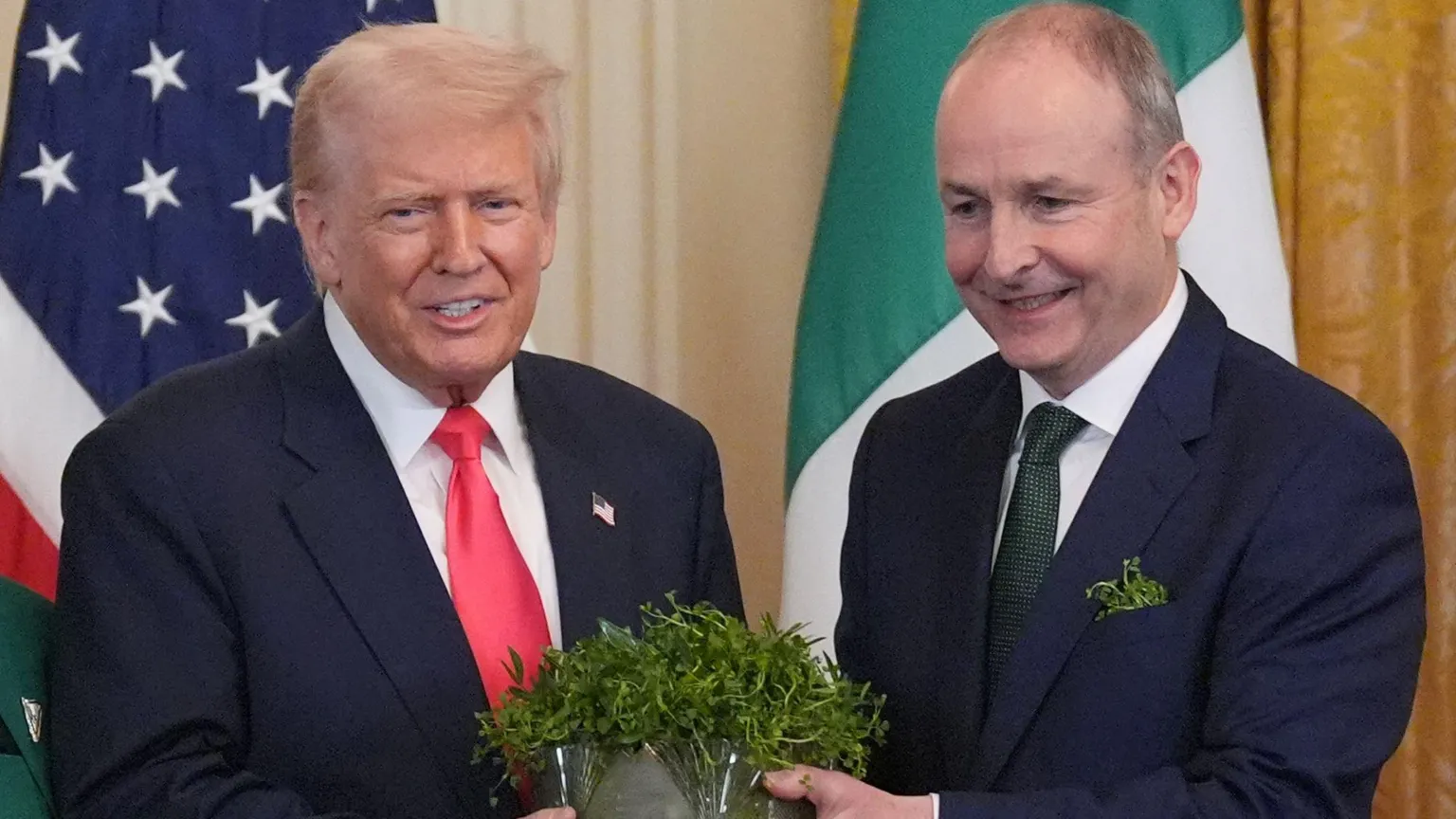 Trump is wearing a dark blazer, white shirt and pink tie. Martin also as a white shirt on but a green tie. His breast pocket is stuffed with shamrock.