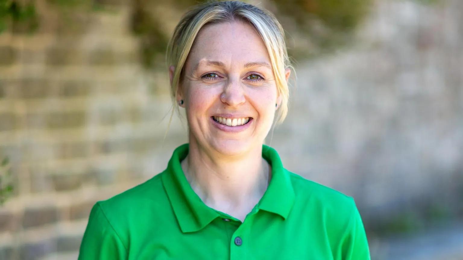 Andy Reeves/PA Wire Kirsty Murray, Heathlands Engagement Ranger for South Downs National Park, smiling for a photo outside. She is wearing a green shirt. A wall can be seen behind her.