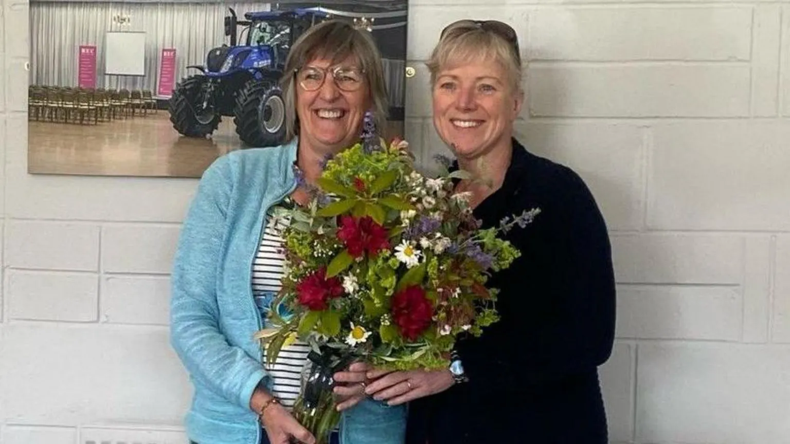 Borders Children's Charity Two ladies smiling at the camera with a bunch of flowers between them.