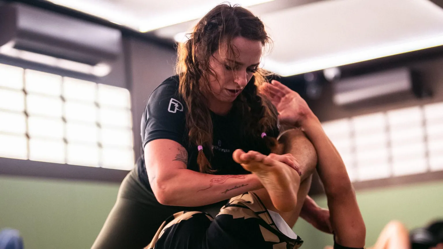 Zuffa UK Ffion Davies in a grappling position during a training session. She has her right arm resting on someone's shin as she tries to submit them during a training session.