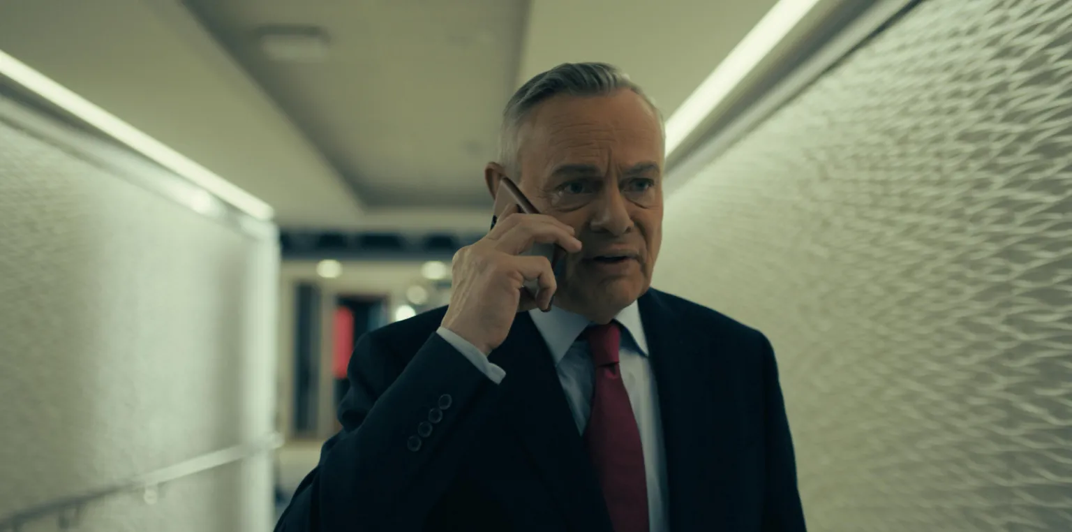 5 Broadcasting Limited / Paramount / Wonderhood Studios/ PA Clunes in a suit with a light blue shirt and red tie. Holding a phone to his right ear