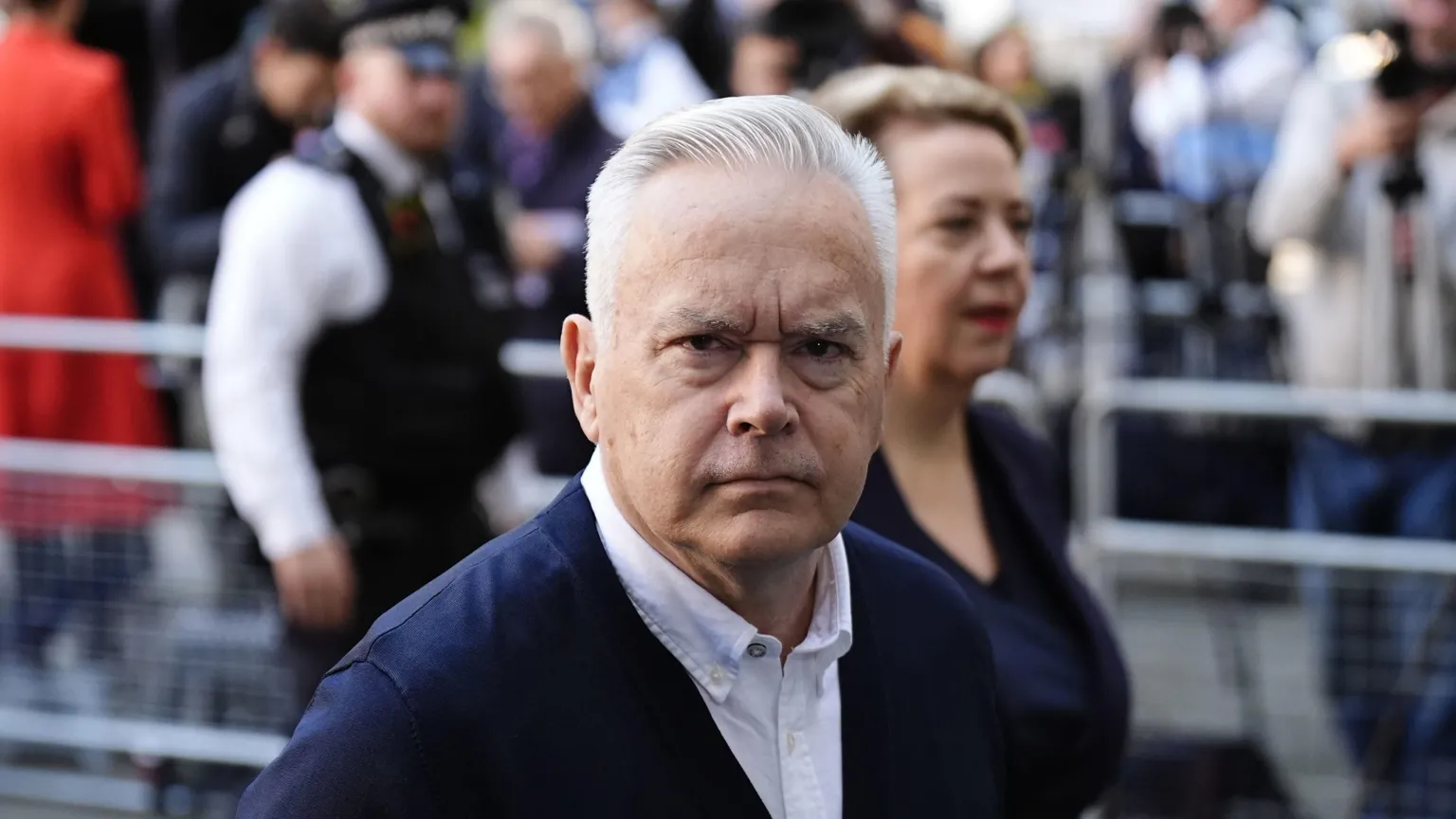  Edwards wears a white shirt and a navy cardigan 