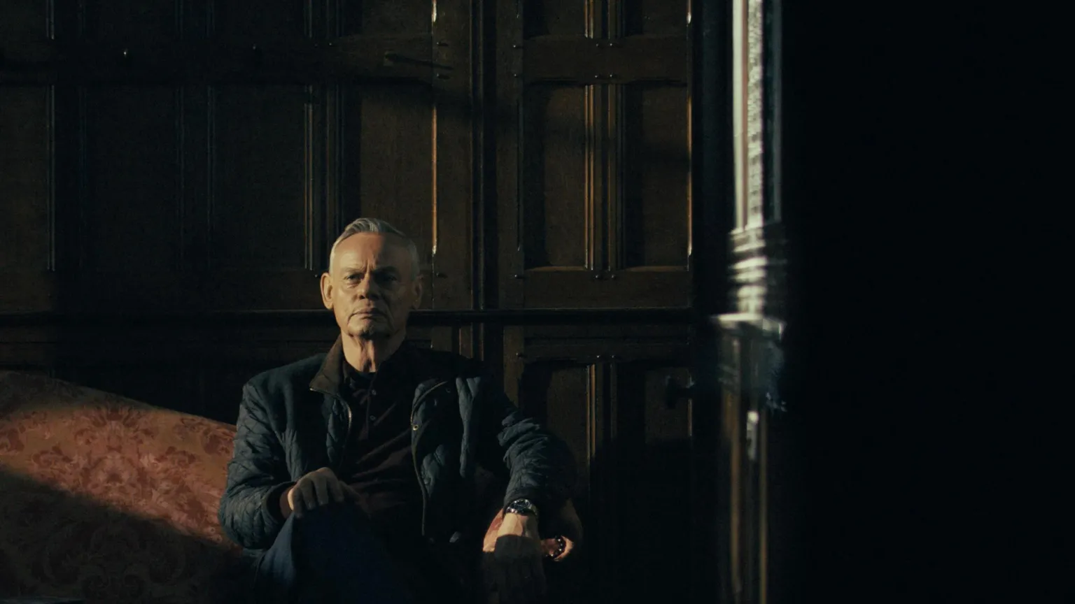 5 Broadcasting Limited / Paramount / Wonderhood Studios/ PA Clunes sat on a red sofa. He wears a brown jumper and black coat