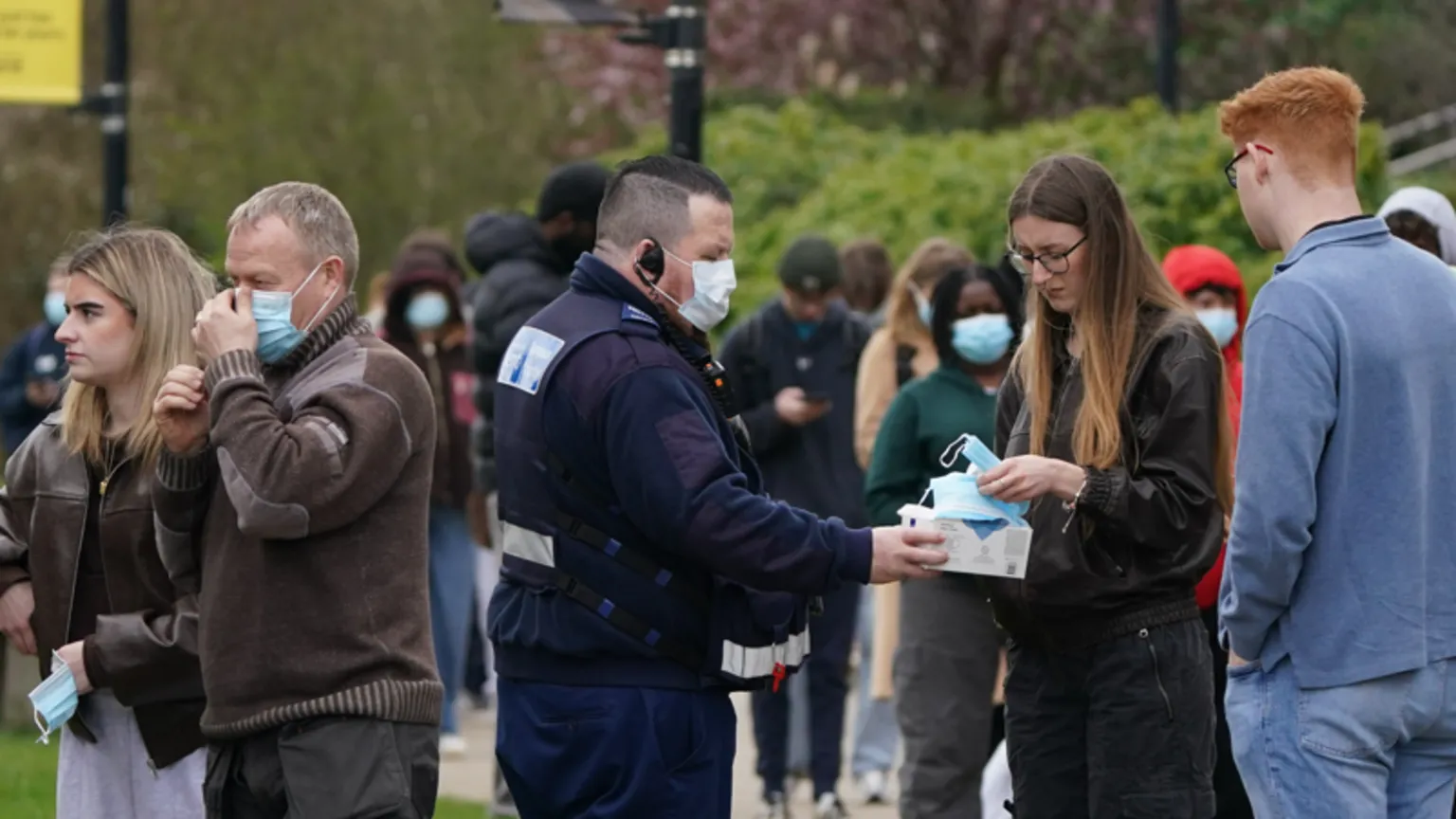  Face masks are given out to students as they queue for antibiotics outside a building at the University of Kent in Canterbury