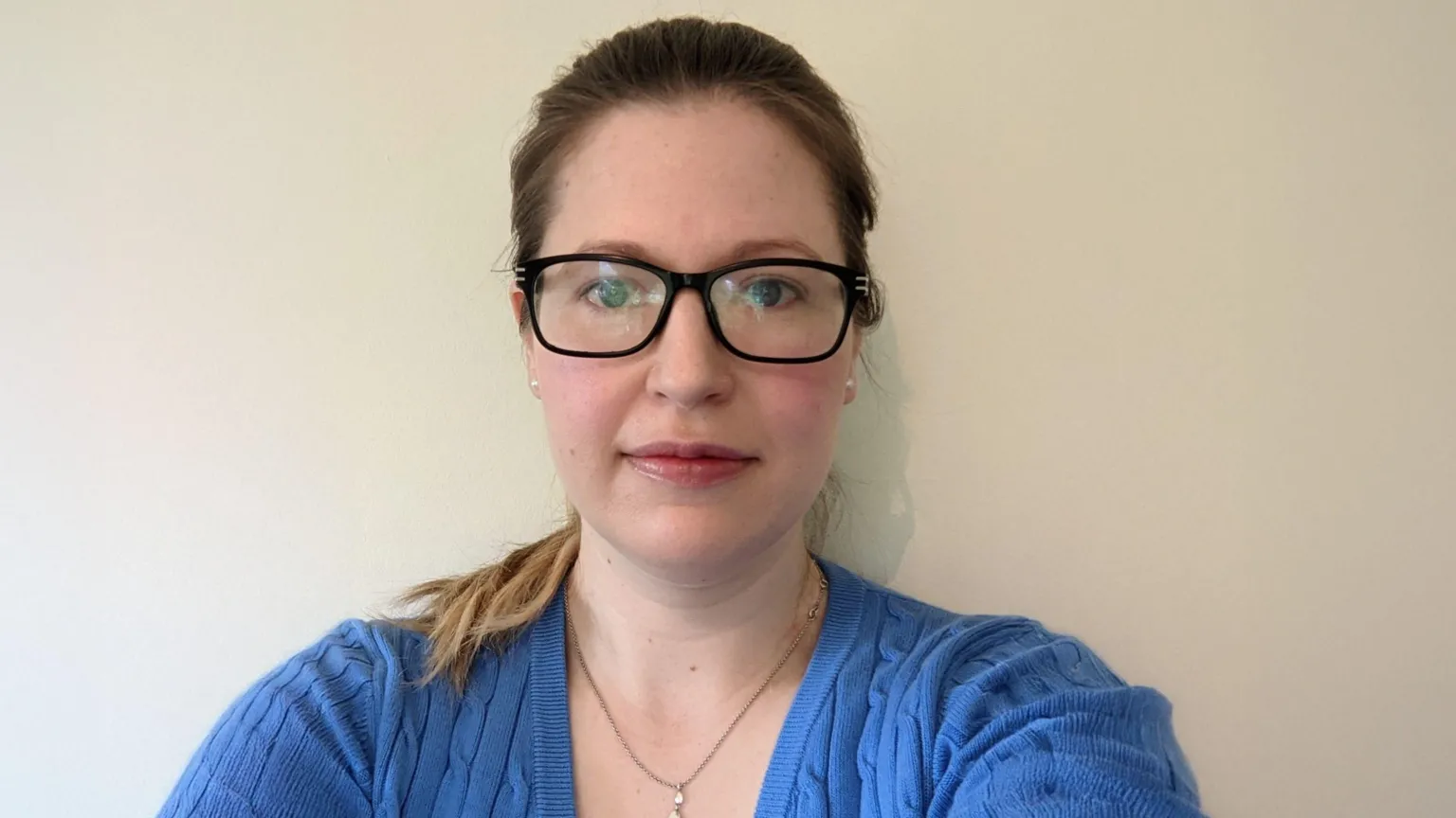 Supplied A woman with her hair tied back wearing a blue jumper and black glasses looking directly at the camera and smiling slightly.