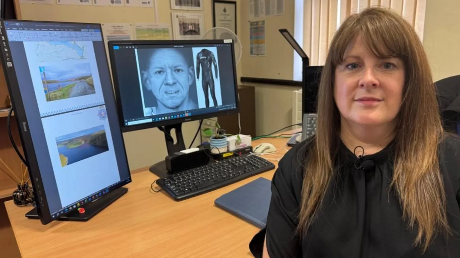 Picture of Detective Inspector Anthea Ponting, who has long brown hair and a fringe. She is sat in a office alongside a computer screen showing the digital recreation of missing man's face and the wet suit he was wearing when found.
