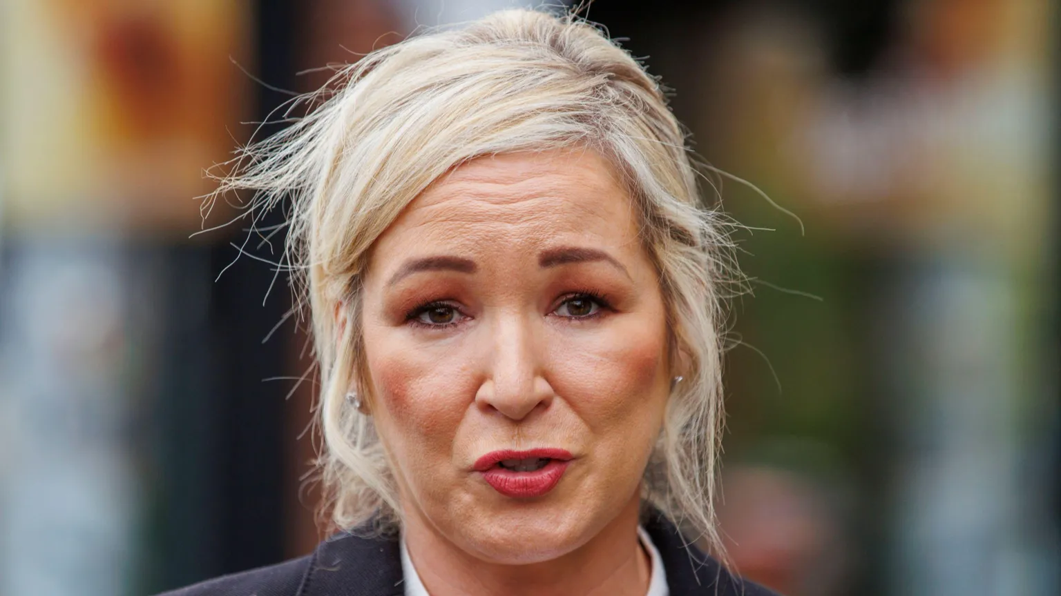  First Minister Michelle O'Neill, pictured from the shoulders up, with blonde hair, tied up. 