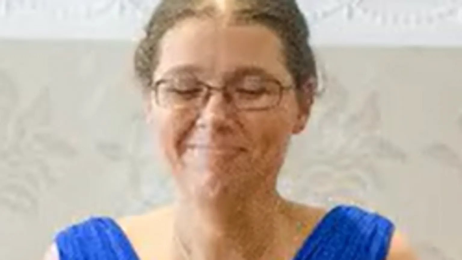 Family photo A close of Steffie Davies wearing a blue dress at her sisters wedding. She wears glasses and her brown hair is tied back. 