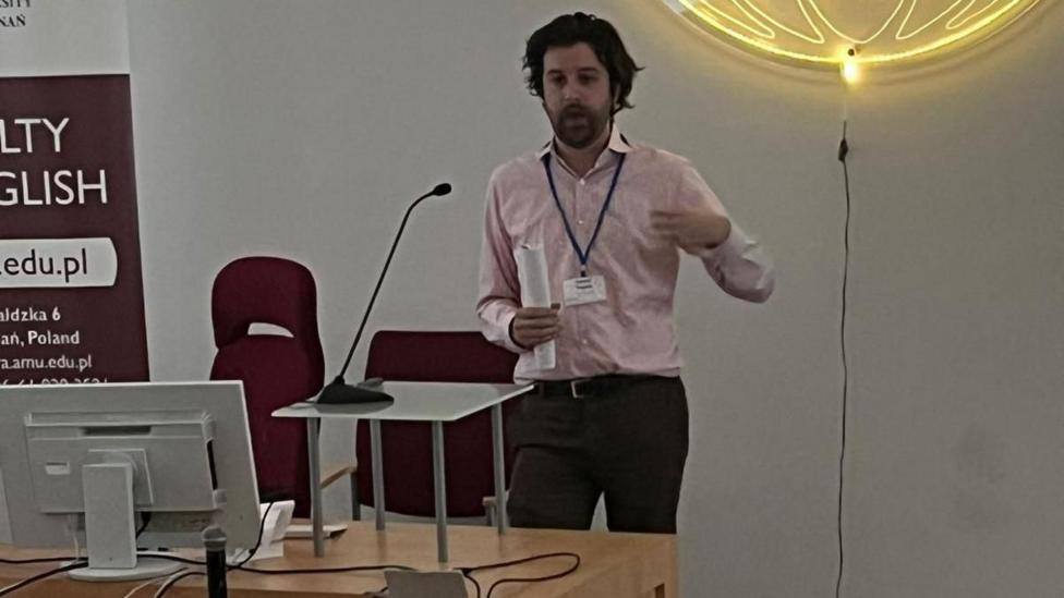 Samuel yn darlithio yng Ngwlad Pwyl