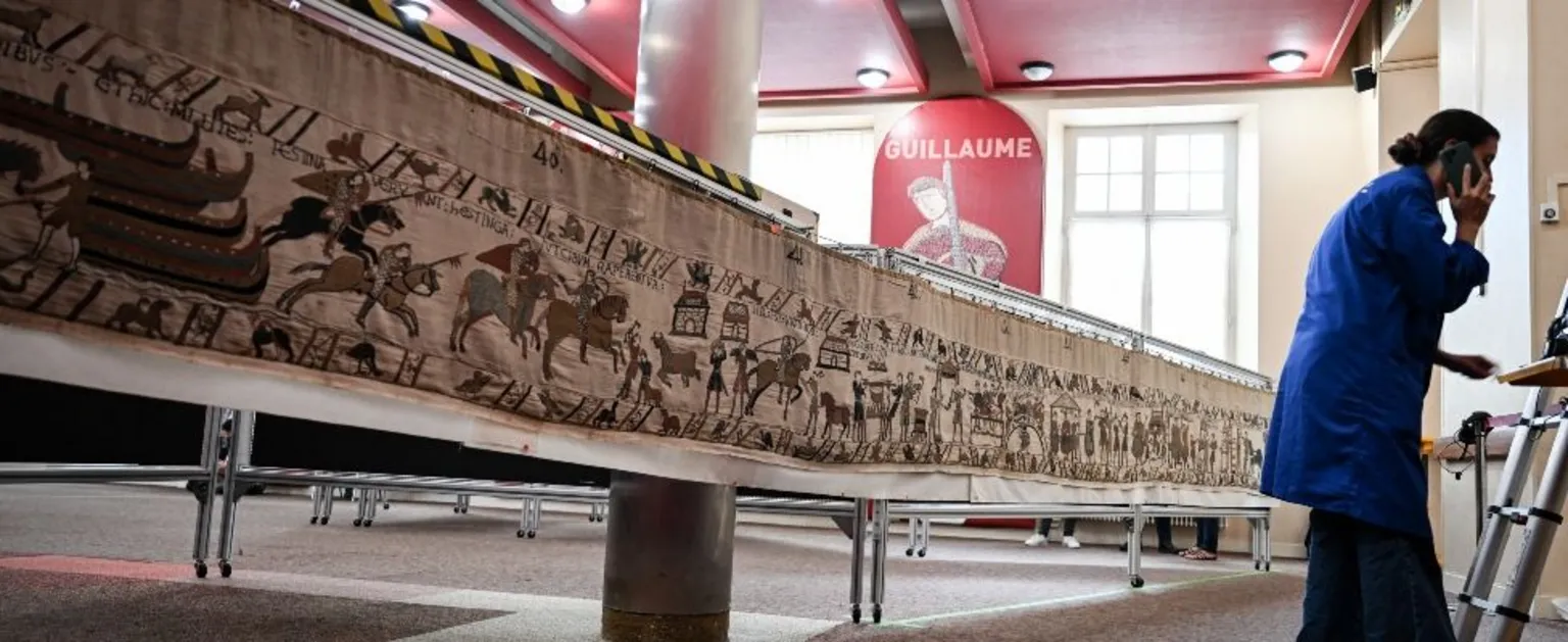  A worker talks to her mobile phone before preparing to pack the Bayeux Tapestry in a crate for transfer to the British Museum, at the Bayeux Tapestry Museum, in Bayeux, northwestern France, on September 18, 2025. 