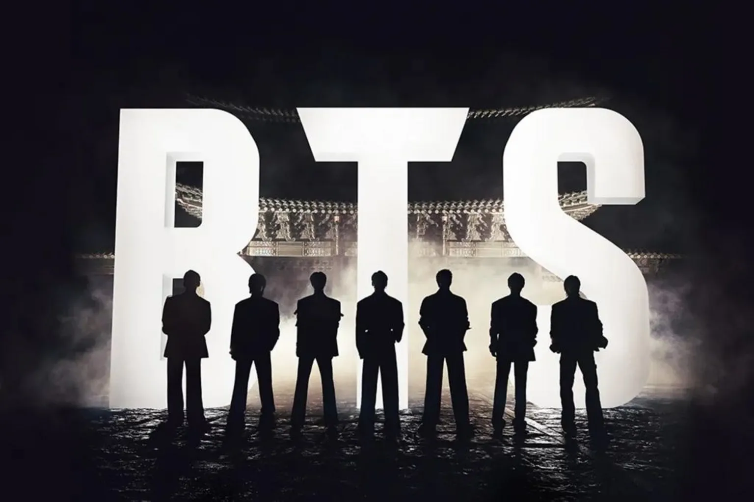 Netflix A promotional photo of BTS. The band are in silhouette, standing in front of a giant illuminated logo of their name