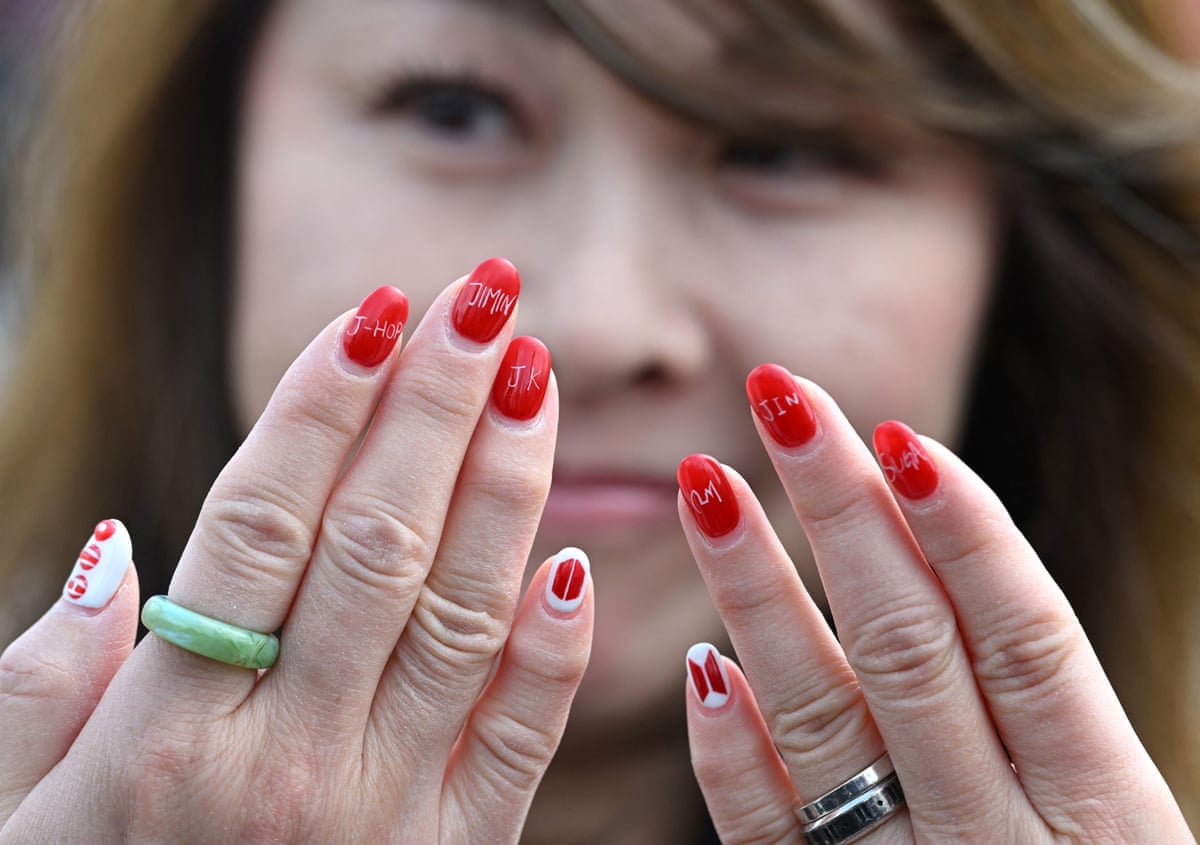 A woman shows nail art featuring the names of BTS members
