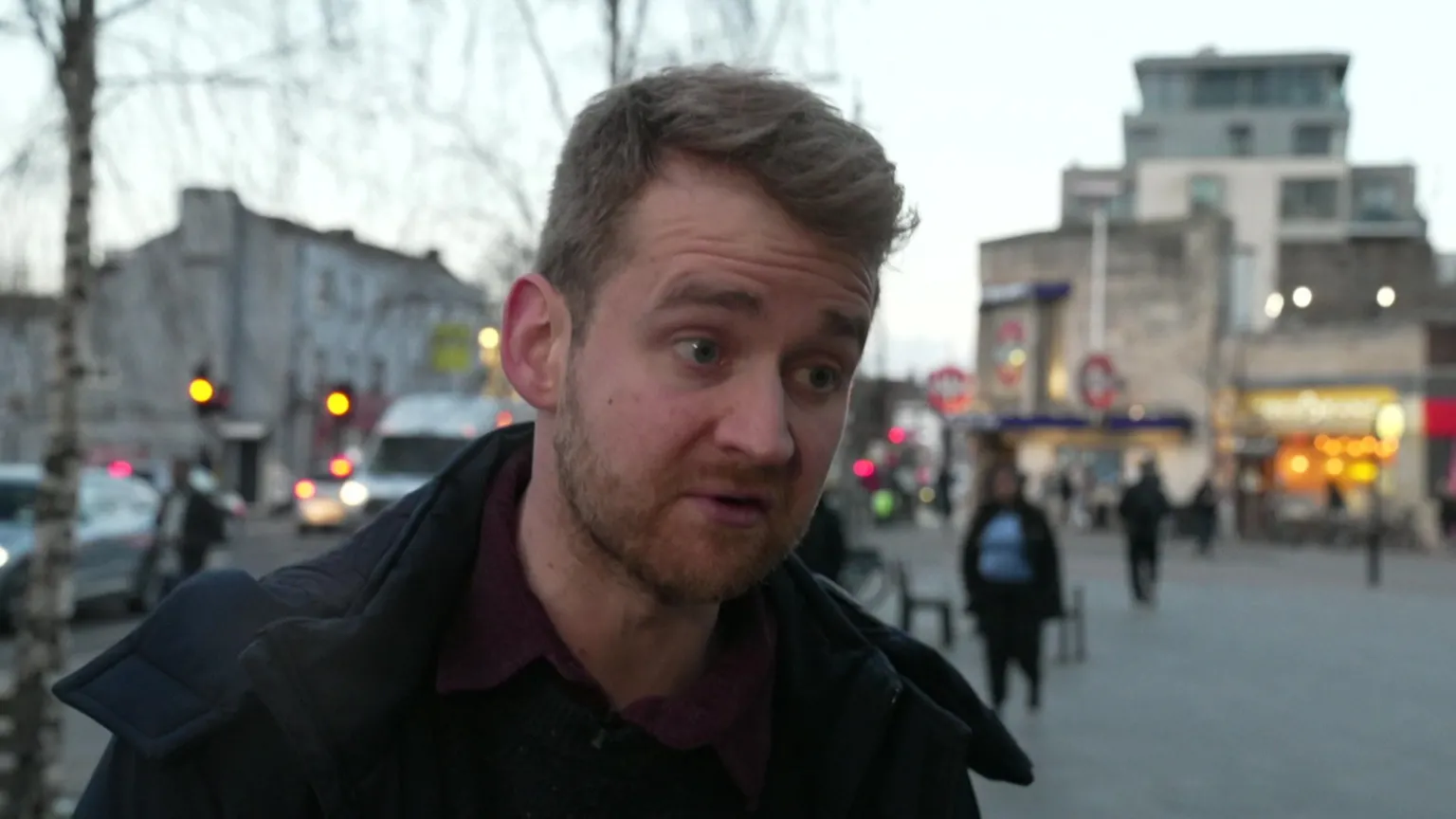 A man in a dark jacket. He has a sandy-coloured cropped beard and dark-blond hair