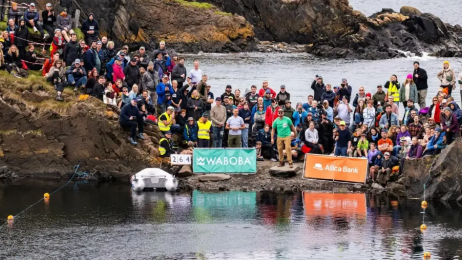 World Stone Skimming Championships Shows a large crowd gathered along a rocky shoreline watching the stone‑skimming event.