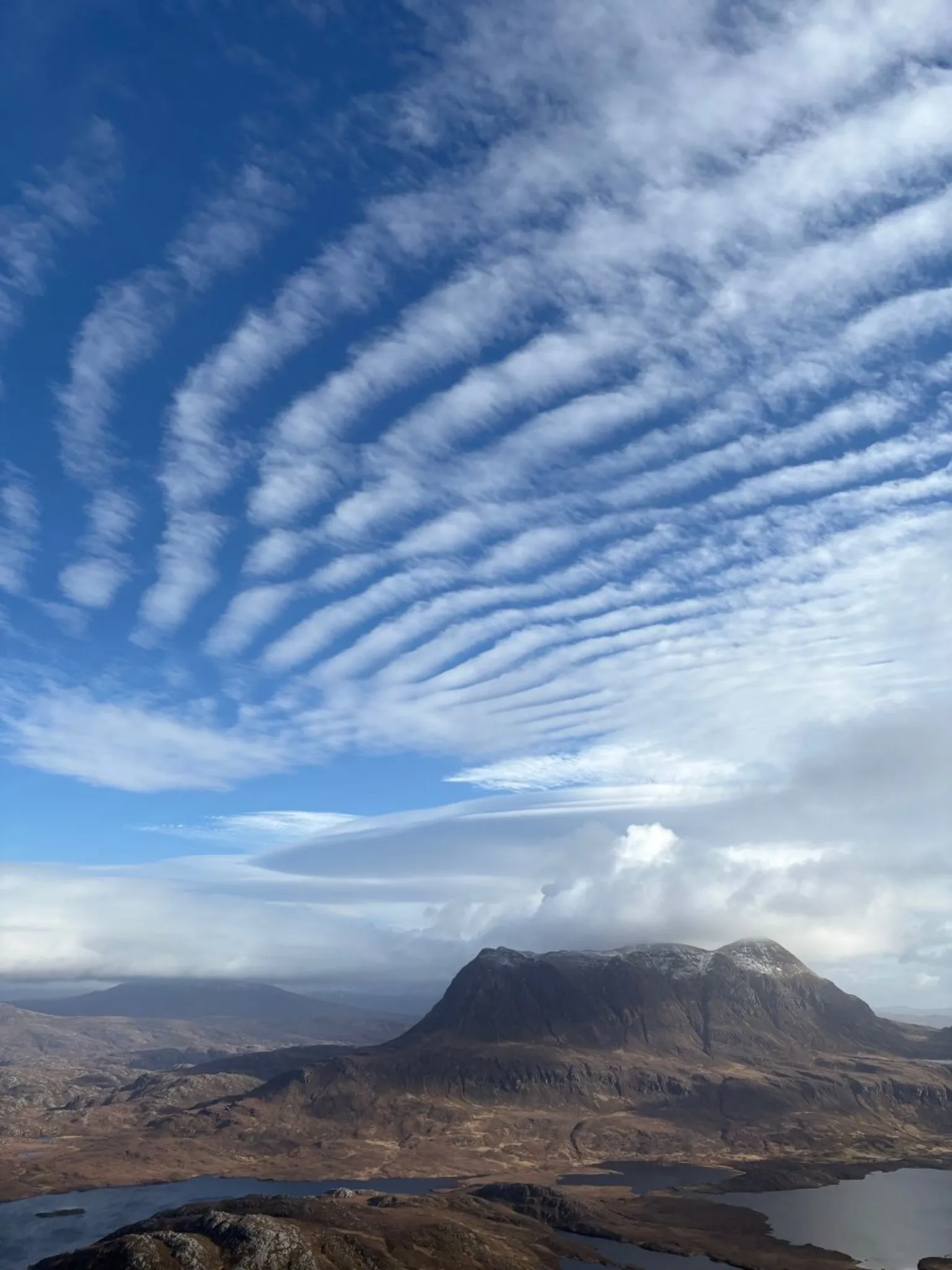 Gordon O'Connor The view from a mountain on a sunny day with patterned clouds in the sky and another mountain in the distance 