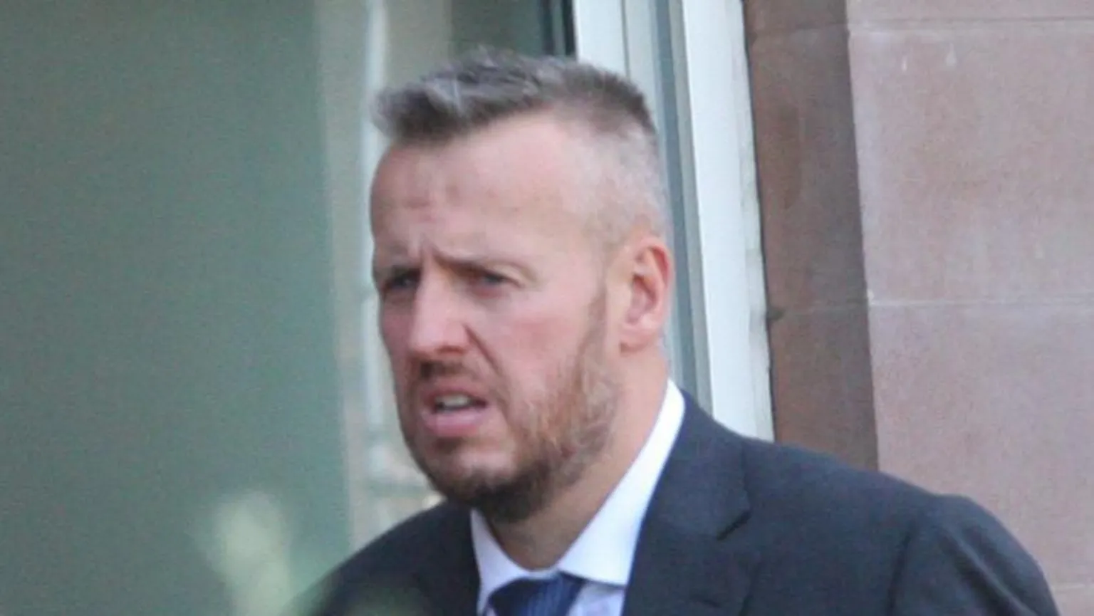 Central Scotland News Agency A man with short spiky hair and beard leaves court, wearing a blue suit and tie
