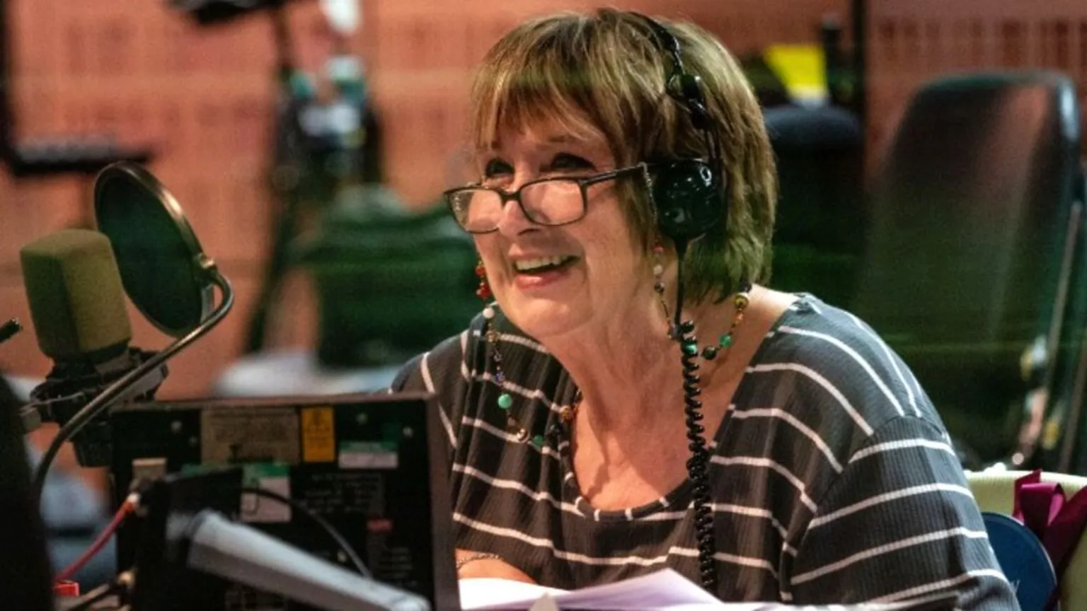 Dame Jenni Murray smiling at the microphone in a BBC radio studio in 2020