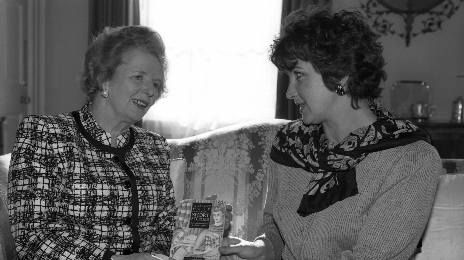 A black and white photo of Margaret Thatcher and Jenni Murray talking on a sofa