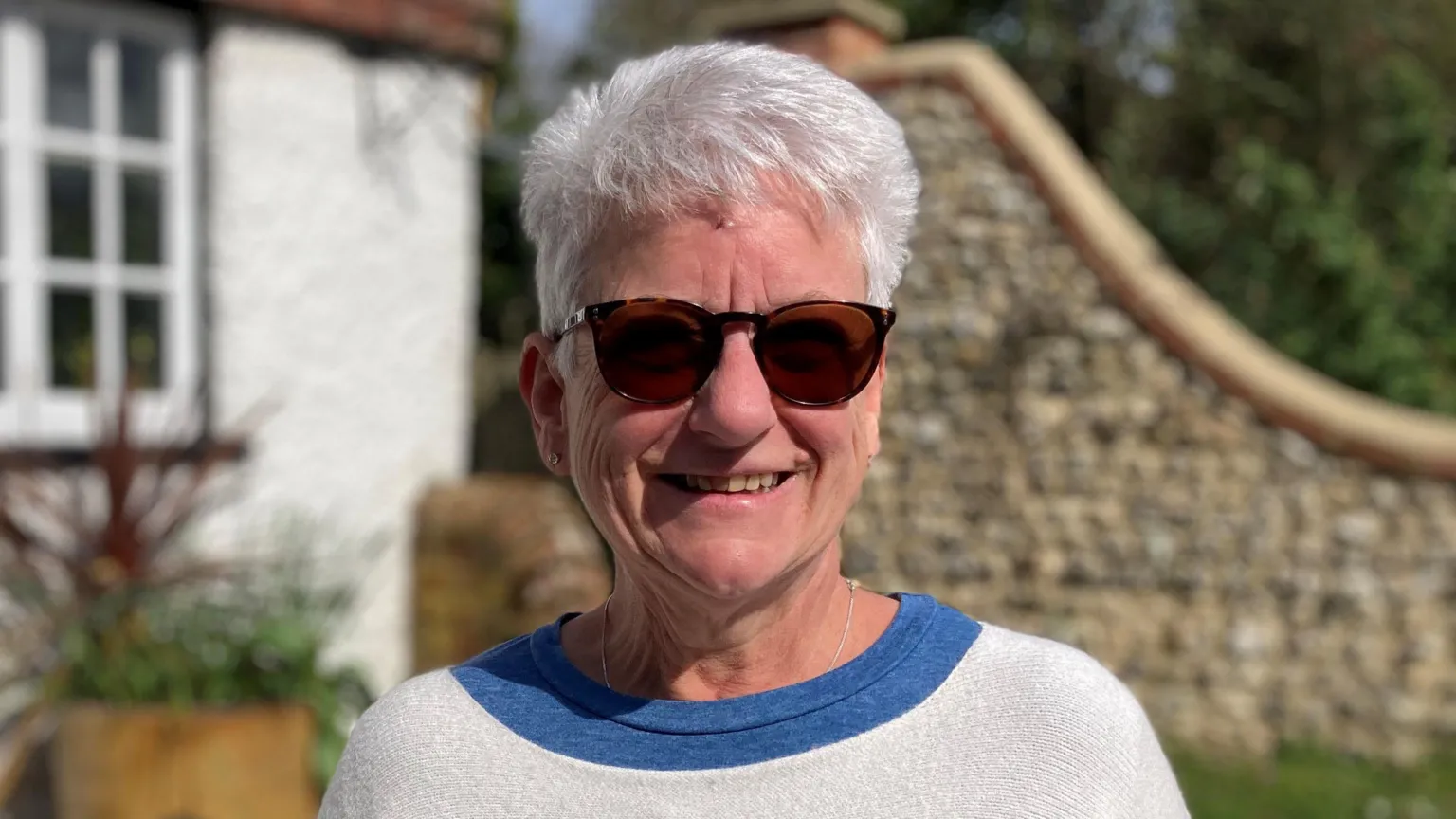Nicky Scott, a woman with short white hair, is pictured smiling at the camera. She is wearing a pair of sunglasses. 