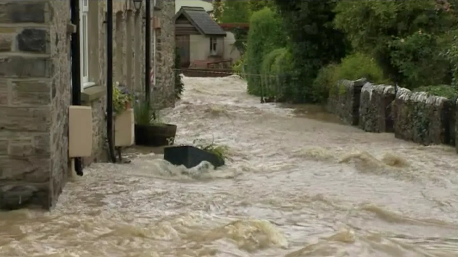Picture of stone wall houses on street with flowing water.
