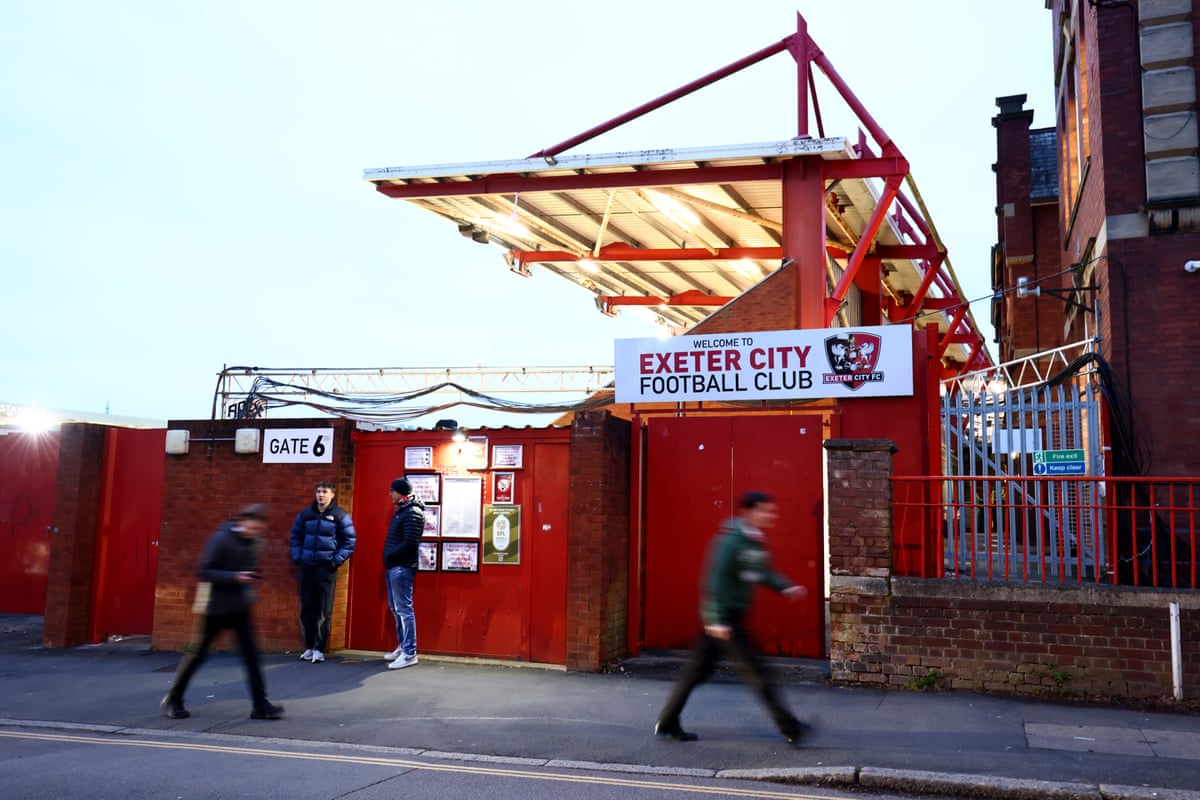 Exterior of football stadium with a few fans outside