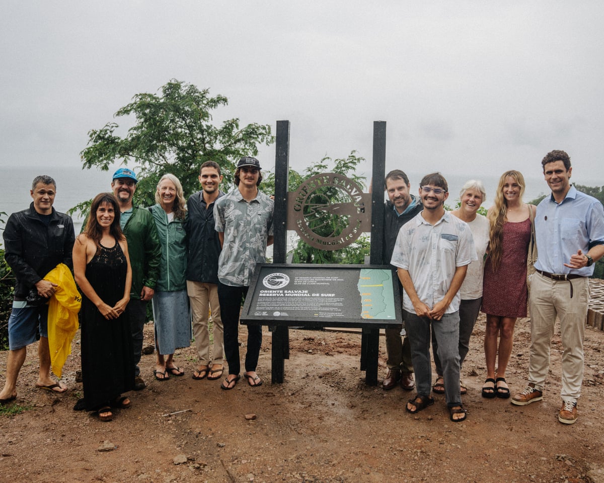 A group of people stand next to an information board on an overcast day