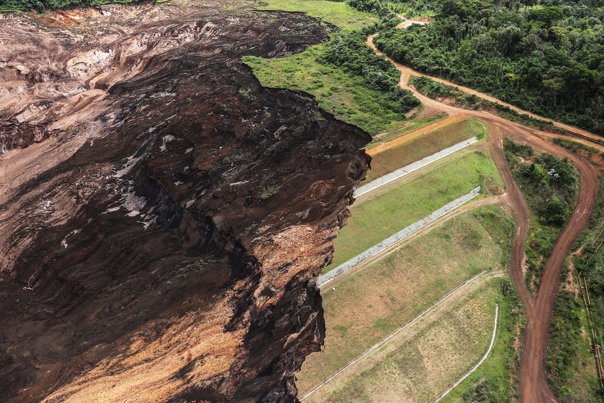 Aerial view of a hillside with a jagged edge where there has been a landslip, with green on one side and black soil on the other