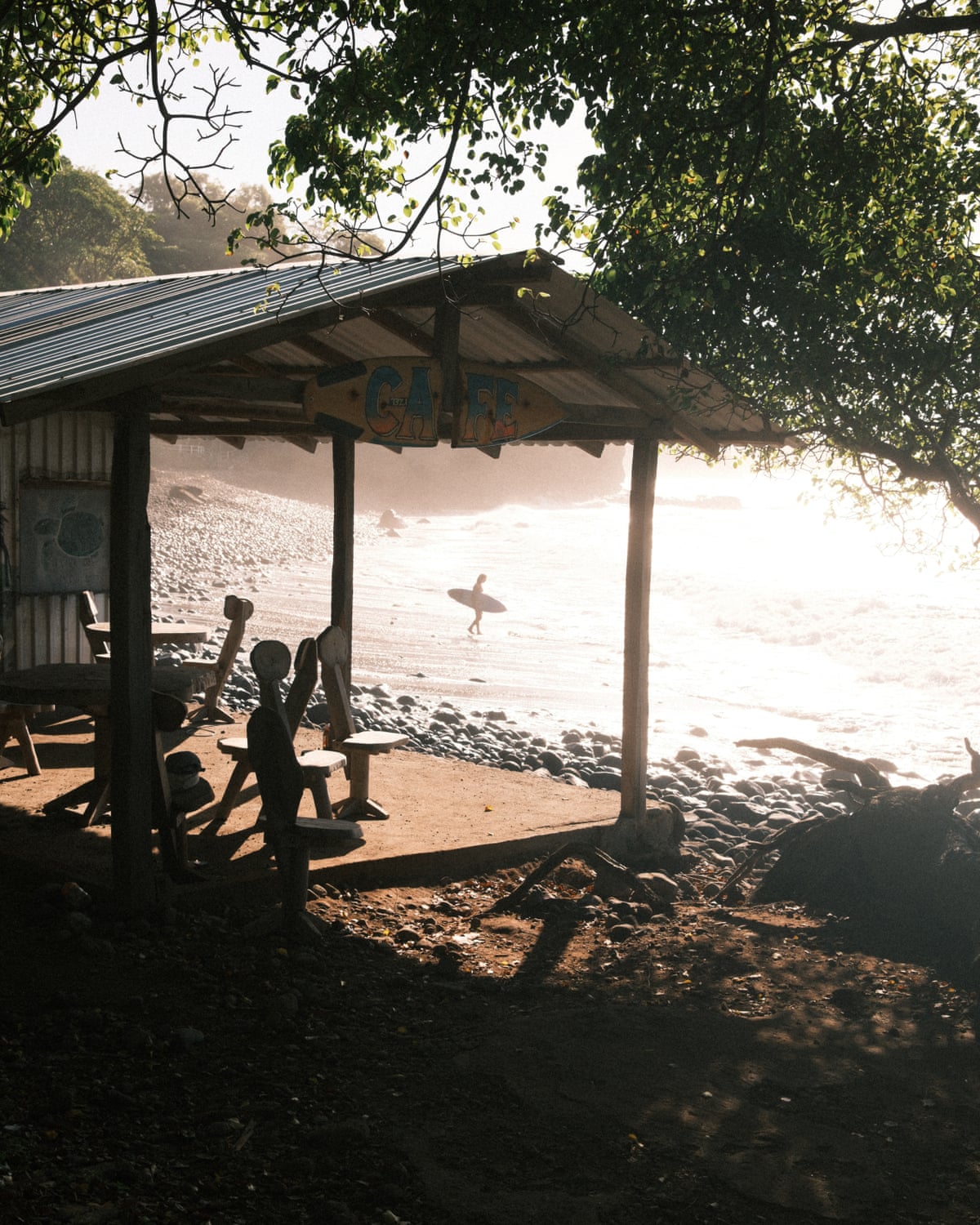 A tin balcony with seats attached to a building which sits on the beachfront.