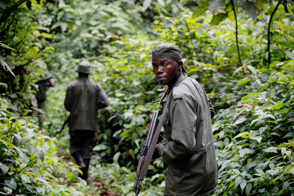 A ranger walking last in a single file line turns to face the camera, his rifle partly raised.
