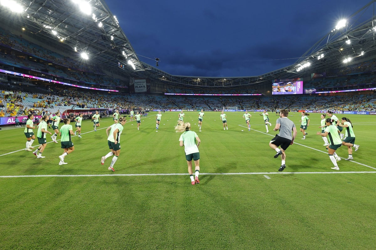 The Matildas warm up beneath a brooding sky at Stadium Australia.