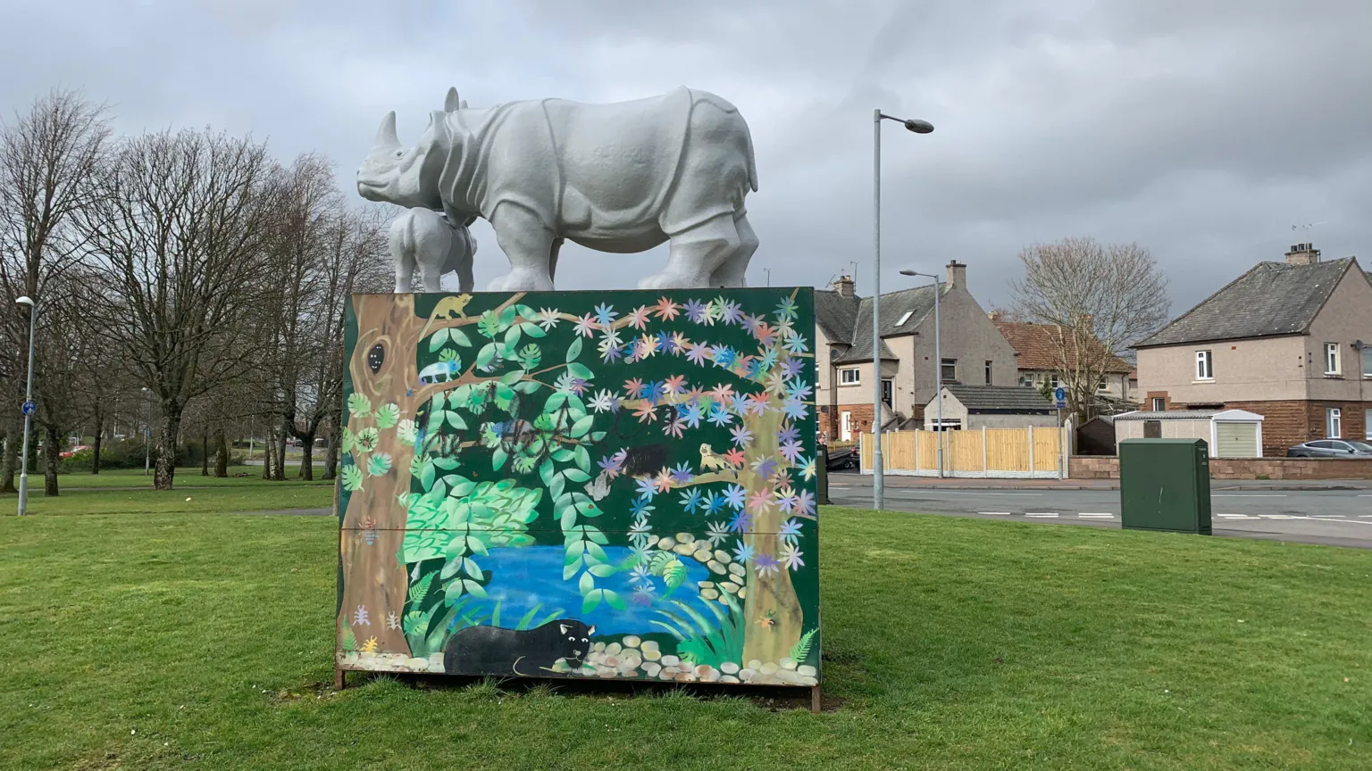 Two fibreglass rhinos on top of a decorated plinth showing a jungle scene with what looks like a leopard