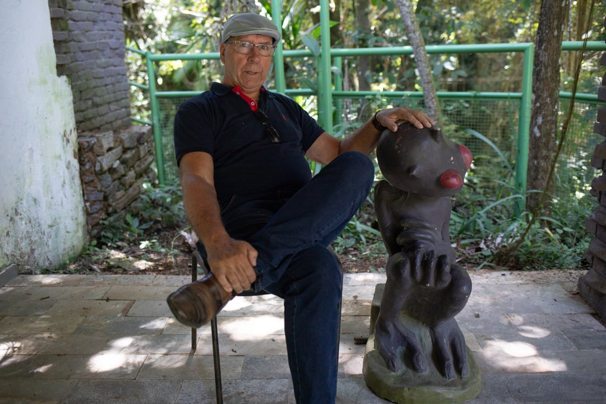 Marco Antônio Reis sits next to a statue of the alien locals apparently saw in Varginha in 1996