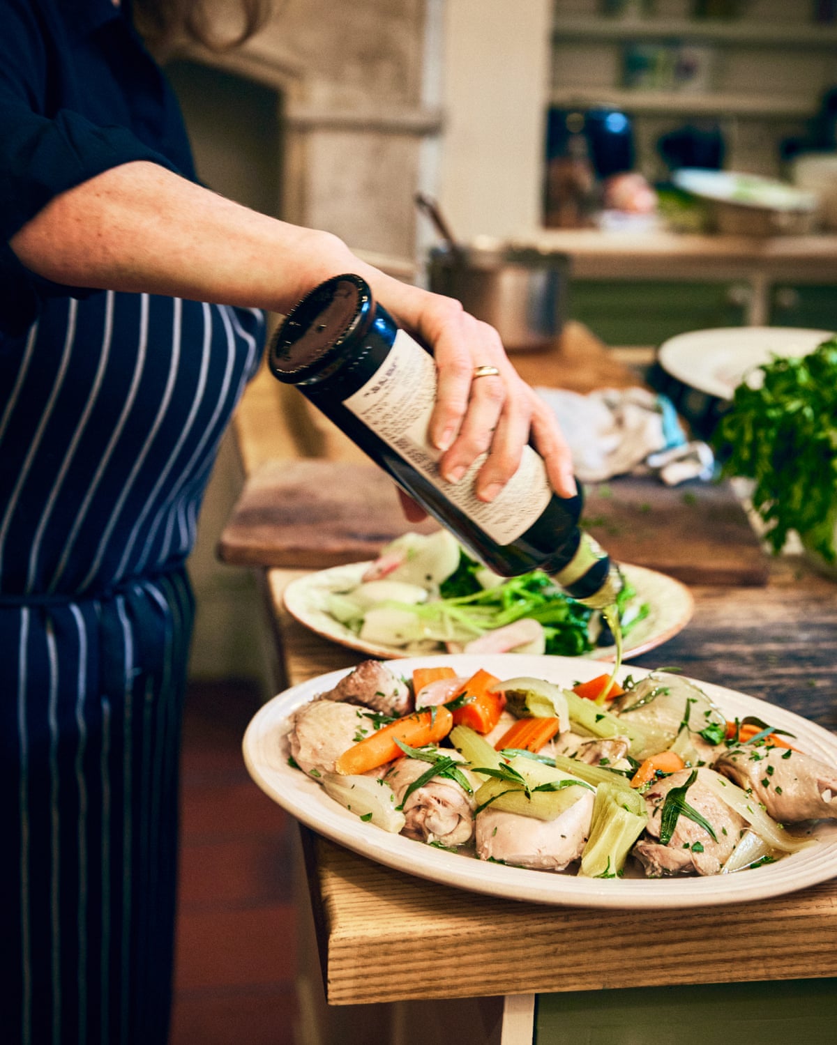 A woman pouring oil onto a chicken dish