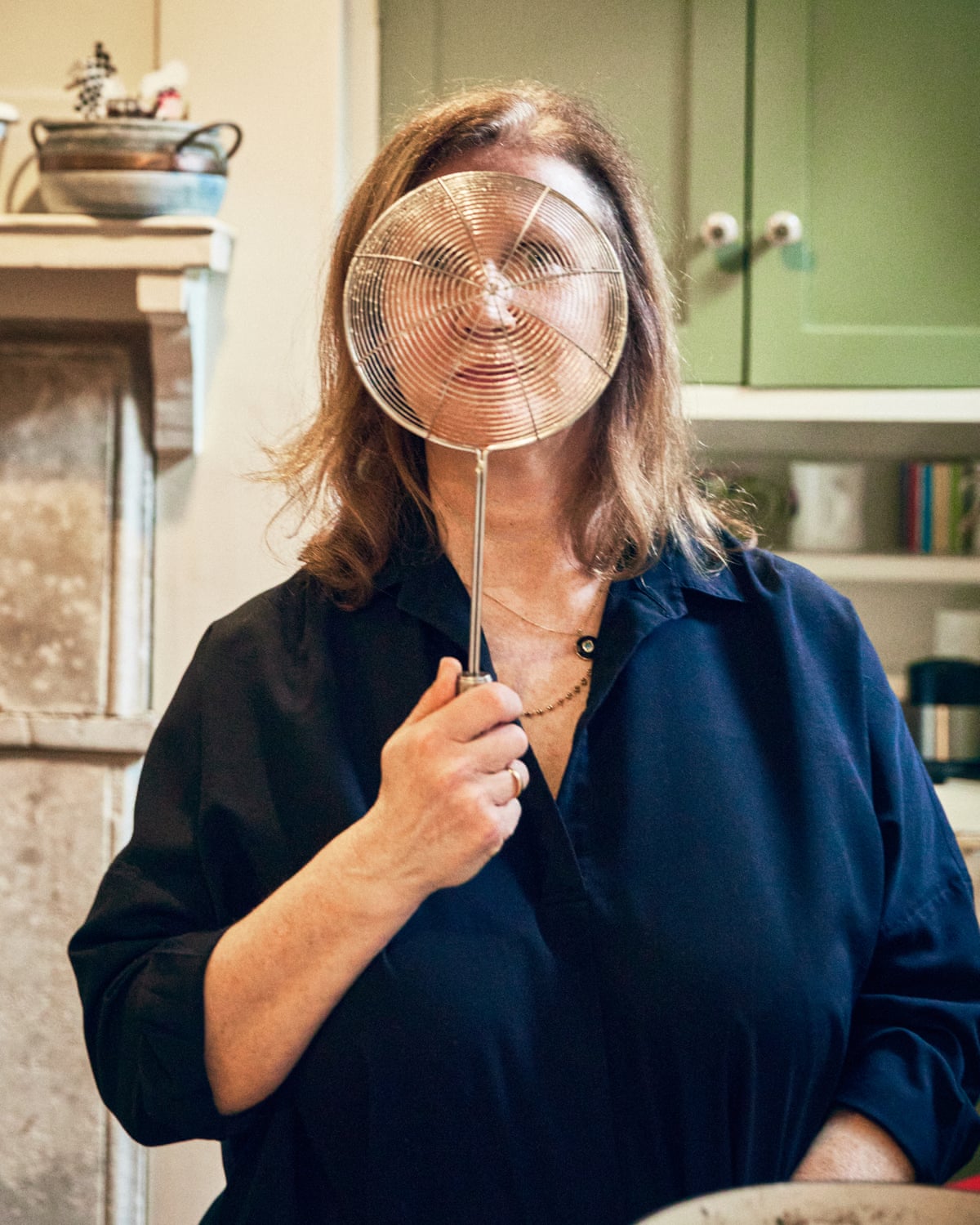 A woman holding a sieve ‘spider’ in front of her face