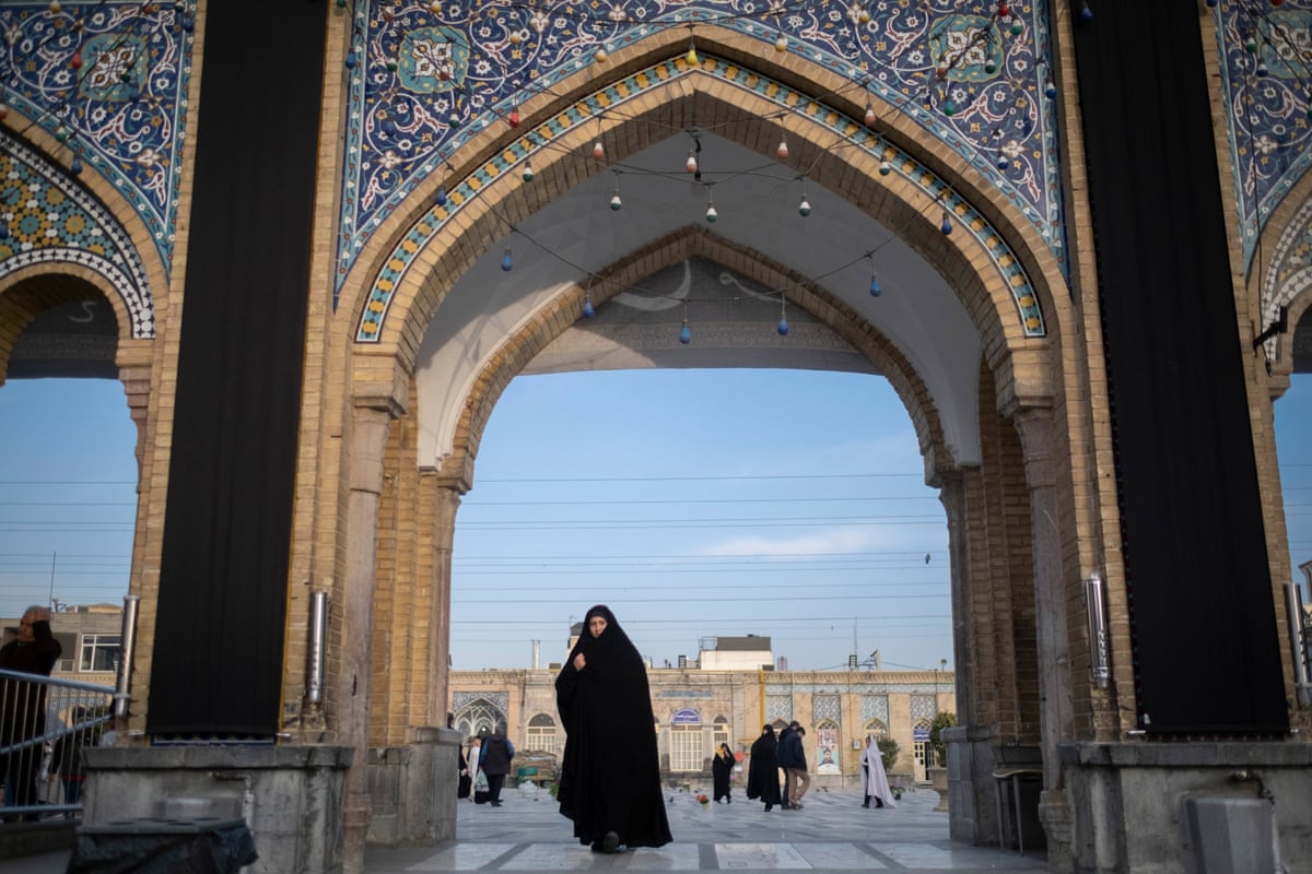 A veiled Iranian woman walks at a holy shrine