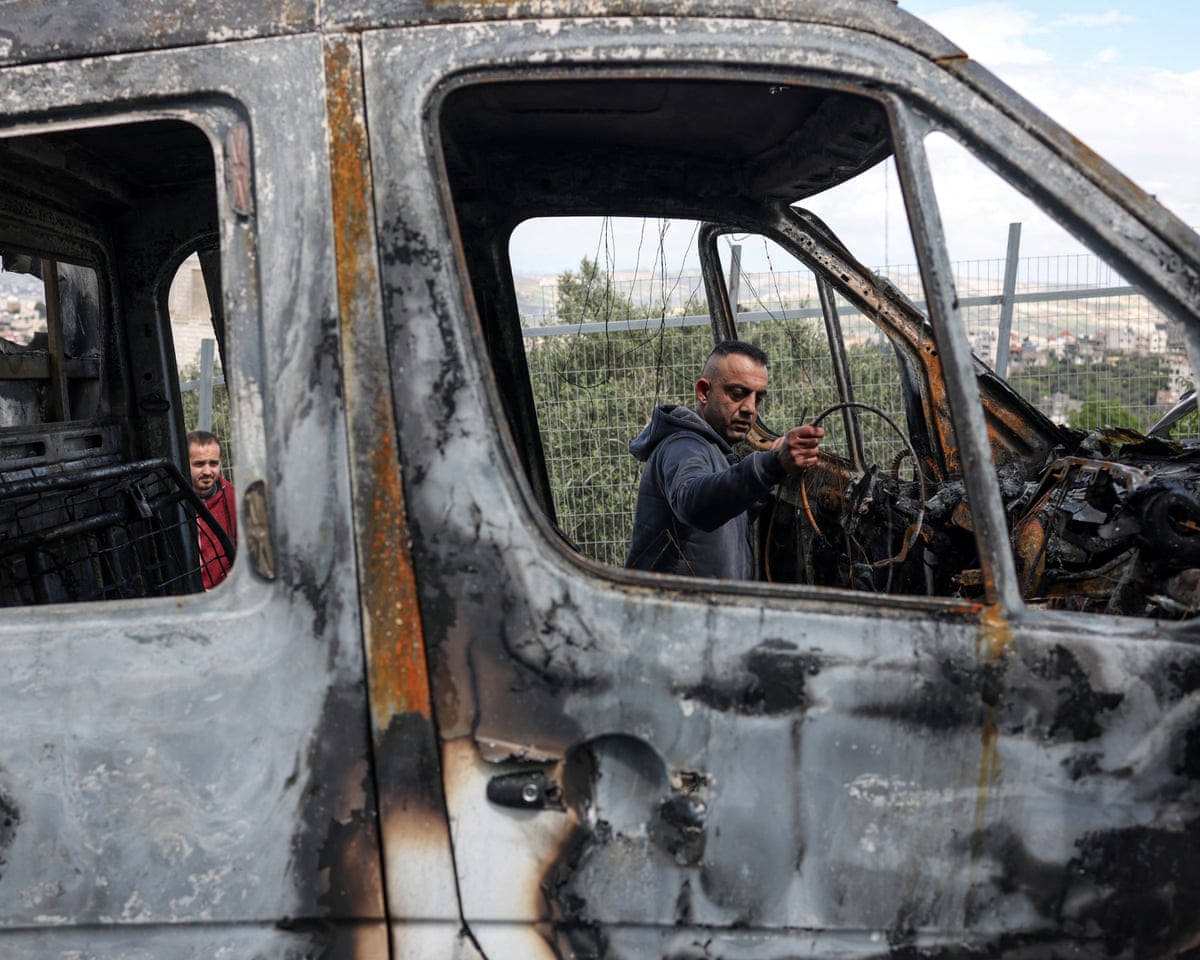 A Palestinian man inspects his burnt-out vehicle