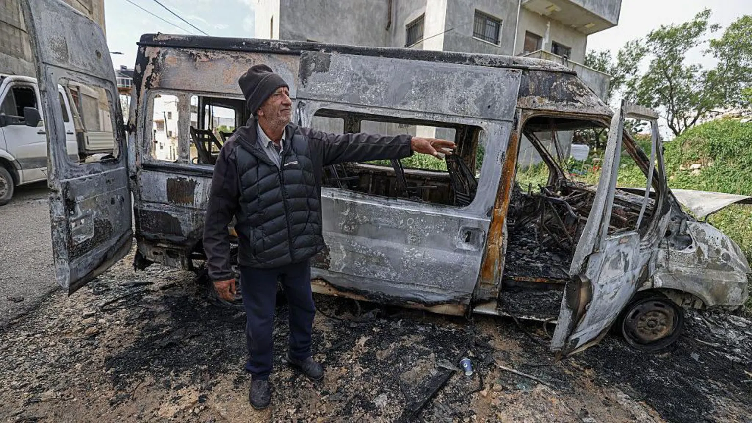 AFP via An elderly man stands next to a burnt-out van.