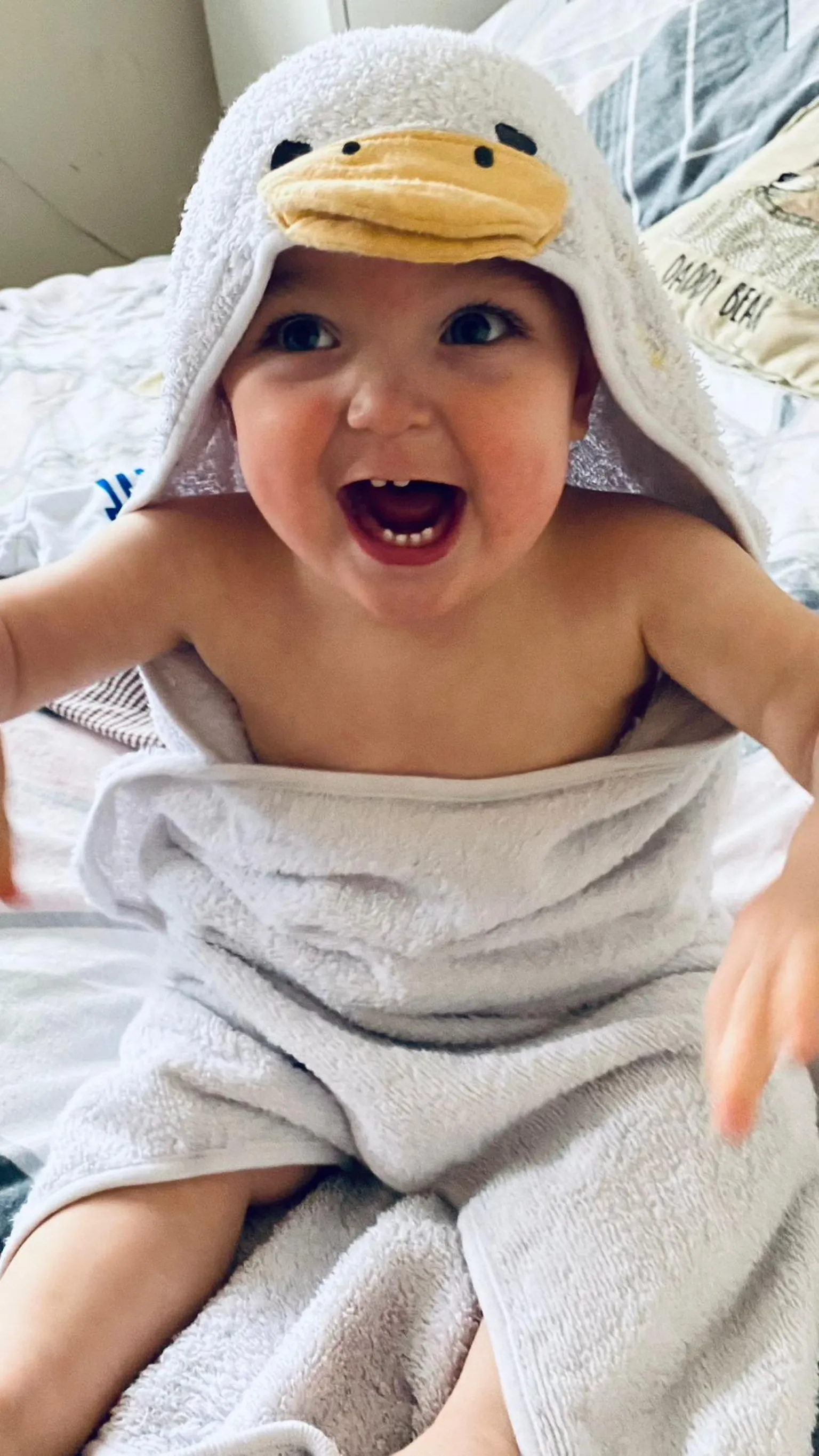 Laura Pridding George laughing, he is wearing a duck towel and is showing his baby teeth.