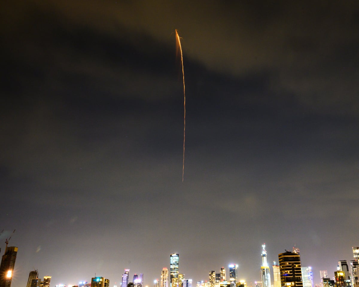 A projectile from an Iranian ballistic cluster munition falls from the sky over the skyline in Tel Aviv on Monday