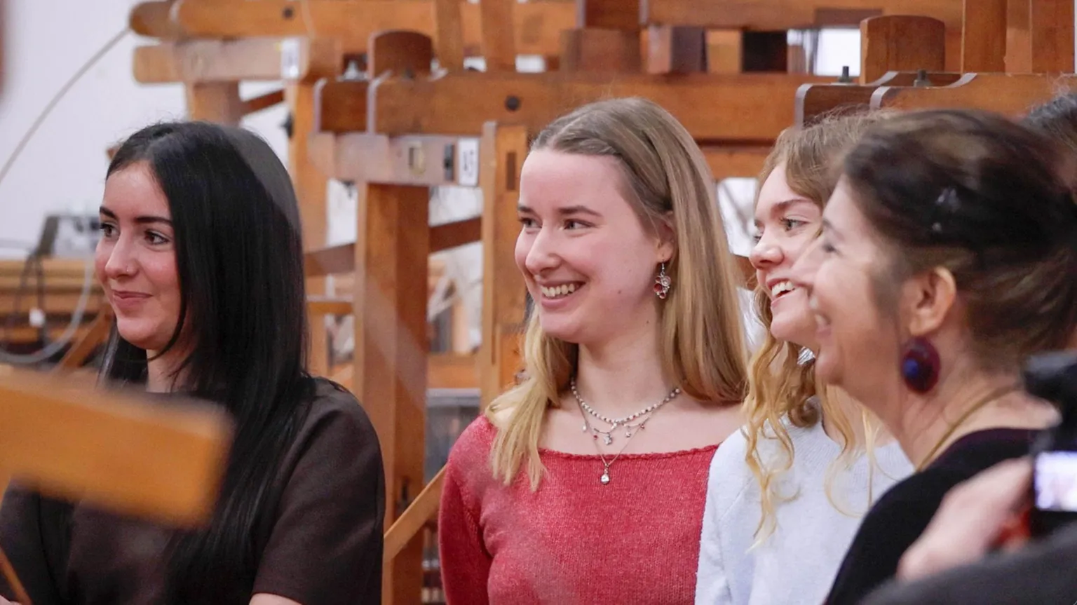 Heriot-Watt University A group of three young women stands smiling - one has dark hair, they other two have lighter blonde hair. Another older woman is closest to the camera with dark hair.